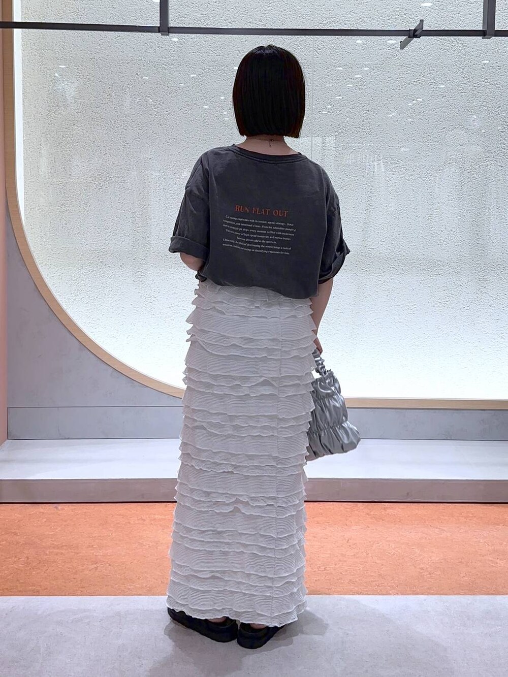 ホワイト系のスカート、グレー系のショルダーバッグ、グレー系のTシャツ/カットソーを着用したレディースの夏コーディネートの3枚目の写真