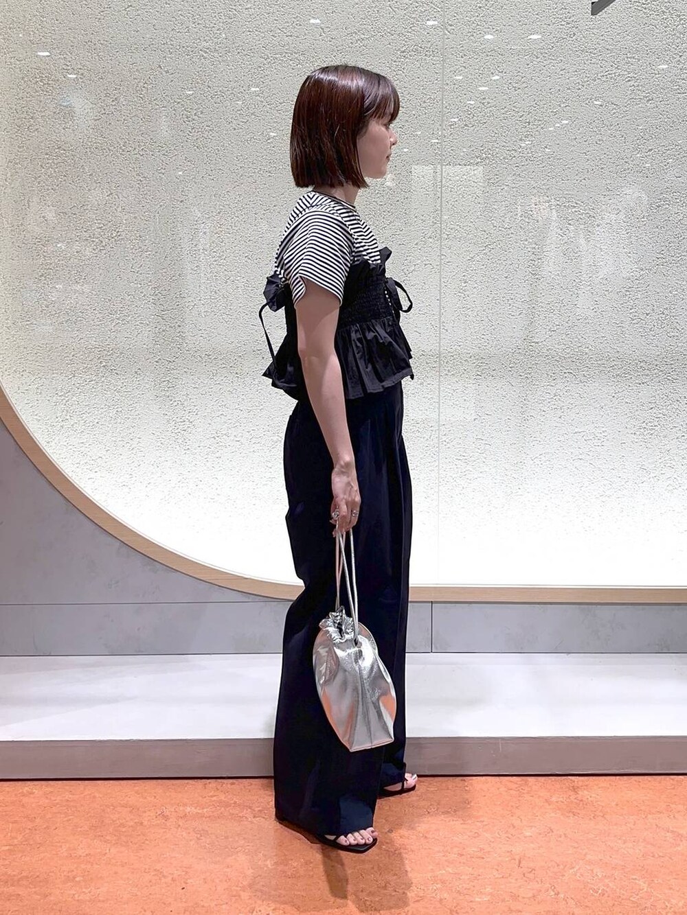 ブルー系のチノパンツ、ブラック系のサンダル、シルバー系のショルダーバッグを着用したレディースの春コーディネートの3枚目の写真