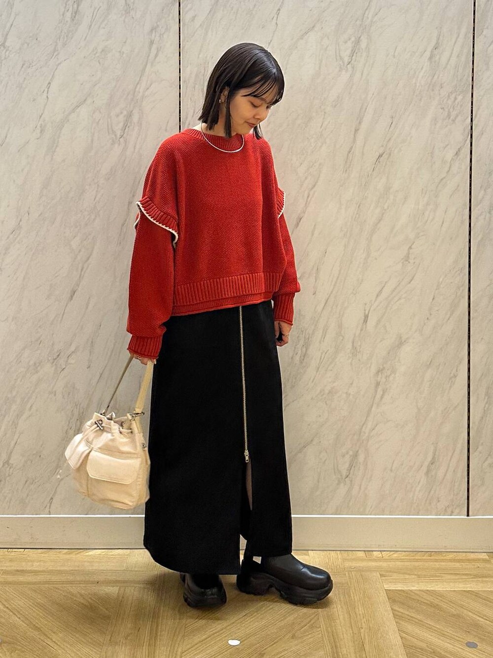 レッド系のニット/セーター、ホワイト系のショルダーバッグ、ブラック系のブーツを着用したレディースの秋コーディネートの3枚目の写真