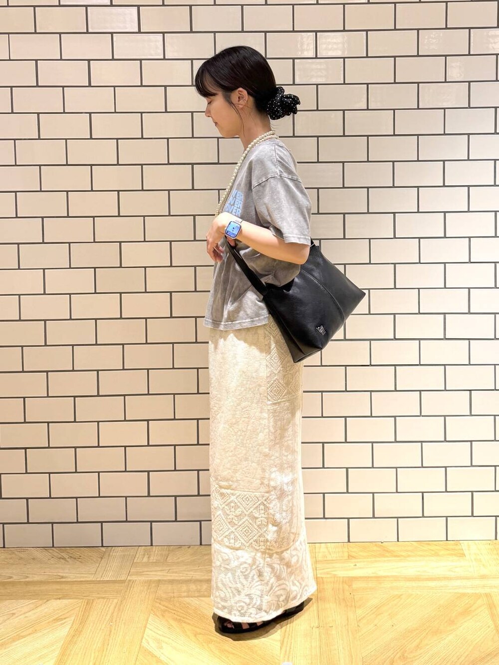 ブラック系のショルダーバッグ、ホワイト系のスカート、ブラック系のサンダルを着用したレディースの夏コーディネートの3枚目の写真