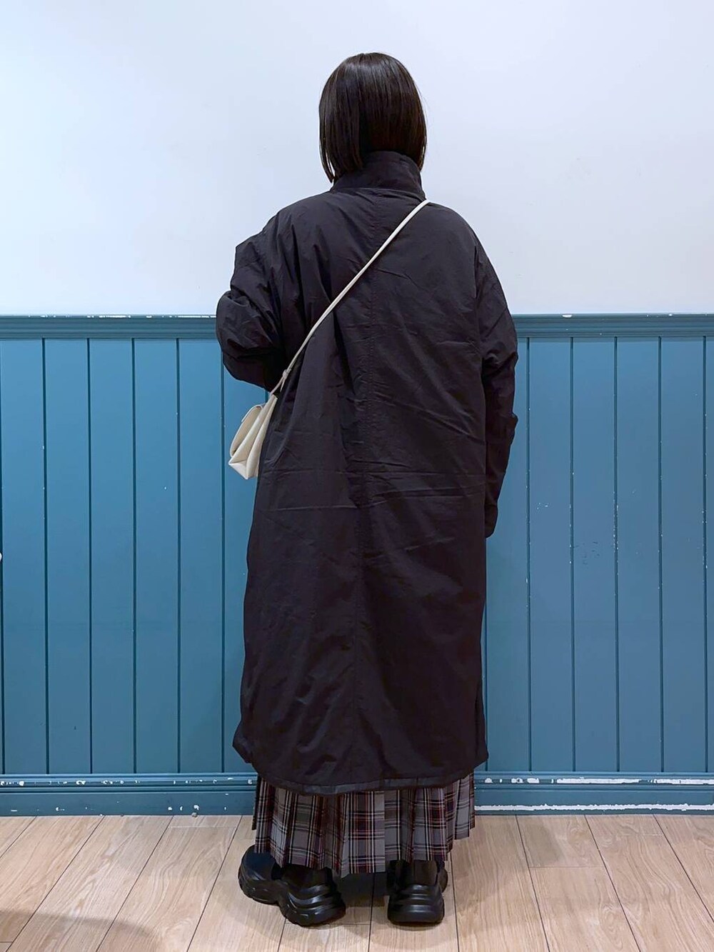 ホワイト系のショルダーバッグ、ブラック系のブーツ、ブラック系のミリタリージャケットを着用したレディースの冬コーディネートの3枚目の写真