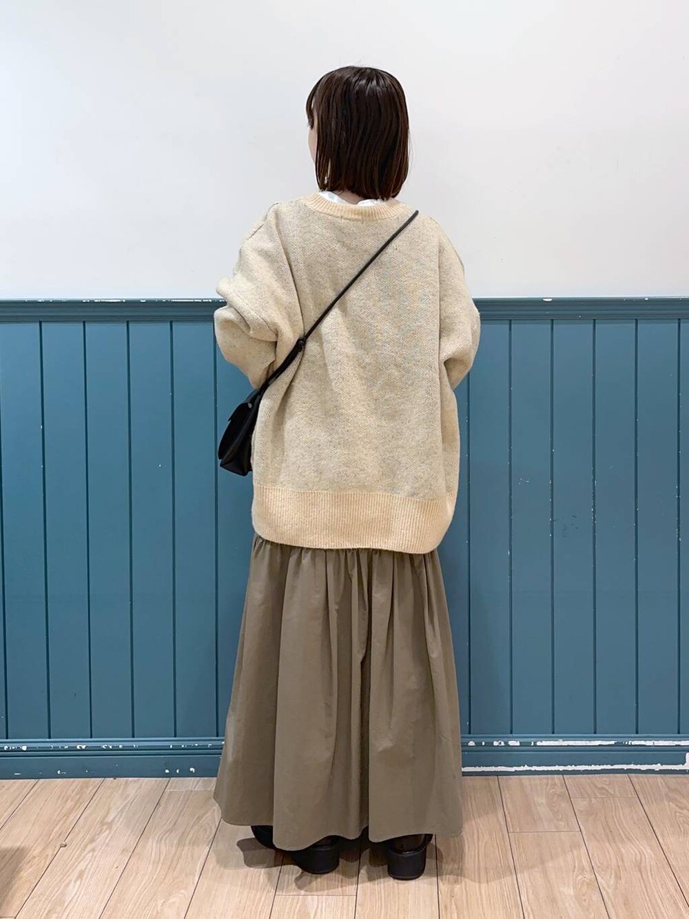 ホワイト系のニット/セーター、ブラック系のショルダーバッグ、グリーン系のスカートを着用したレディースの冬コーディネートの3枚目の写真