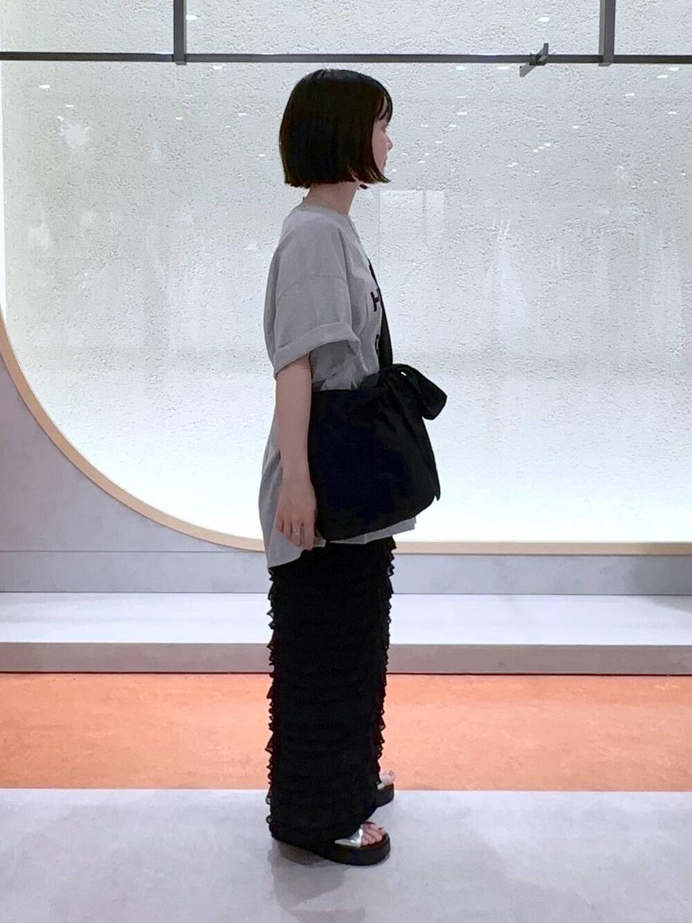 ブラック系のスカート、ブラック系のショルダーバッグ、シルバー系のサンダルを着用したレディースの夏コーディネートの3枚目の写真