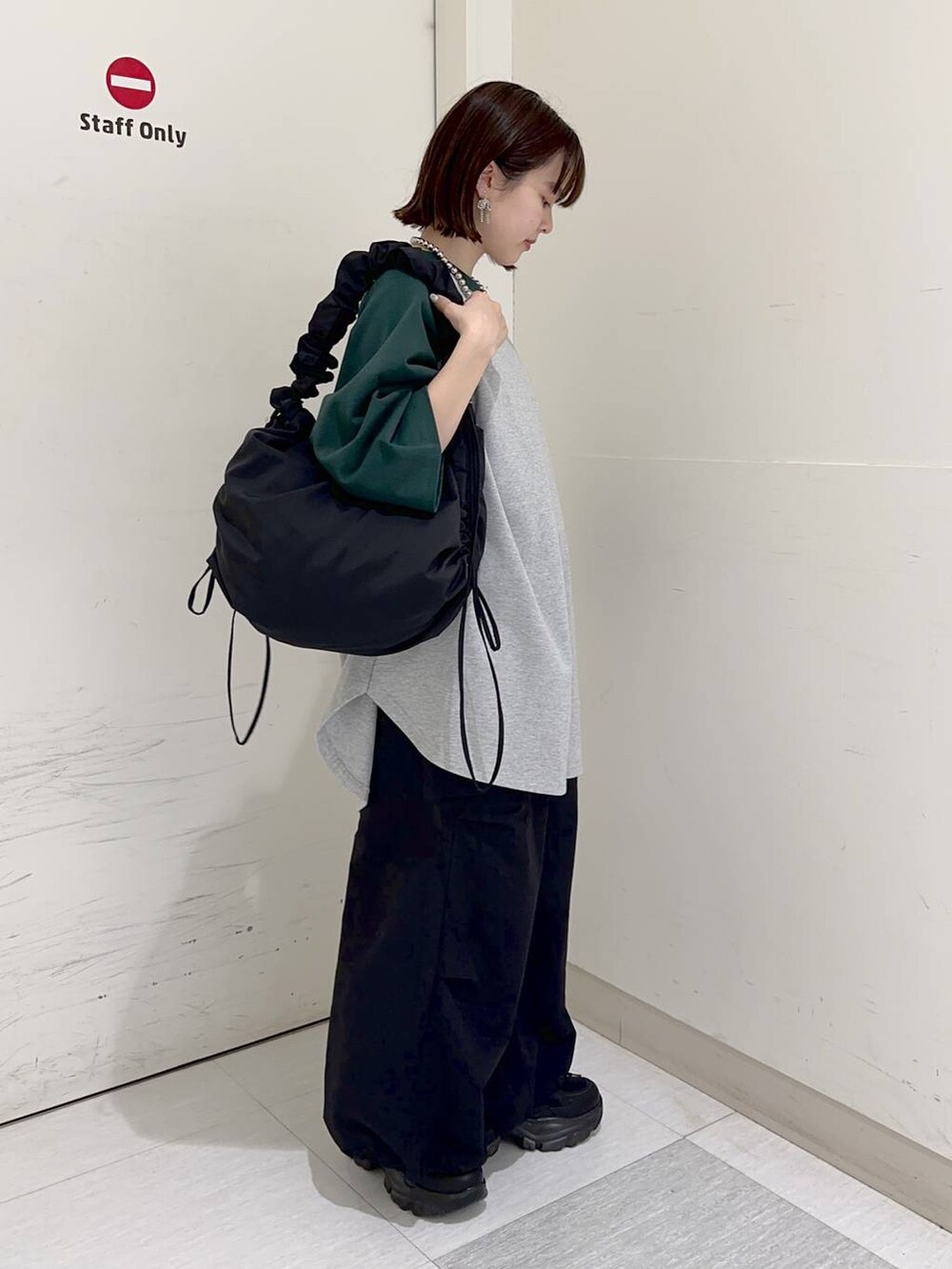 グリーン系のTシャツ/カットソー、ブラック系のショルダーバッグ、グレー系のスウェットを着用したレディースの冬コーディネートの3枚目の写真