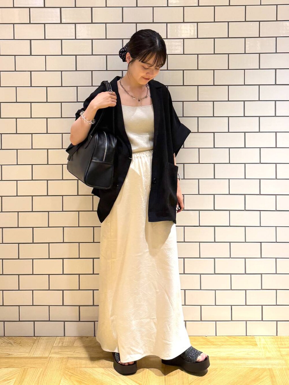 ブラック系のサンダル、ホワイト系のスカート、シルバー系のタンクトップを着用したレディースの夏コーディネートの2枚目の写真