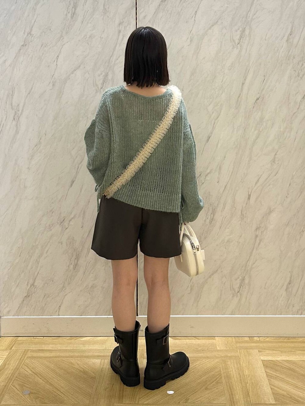 ブラック系のブーツ、ホワイト系のボストンバッグ、グレー系のその他パンツを着用したレディースの秋コーディネートの4枚目の写真