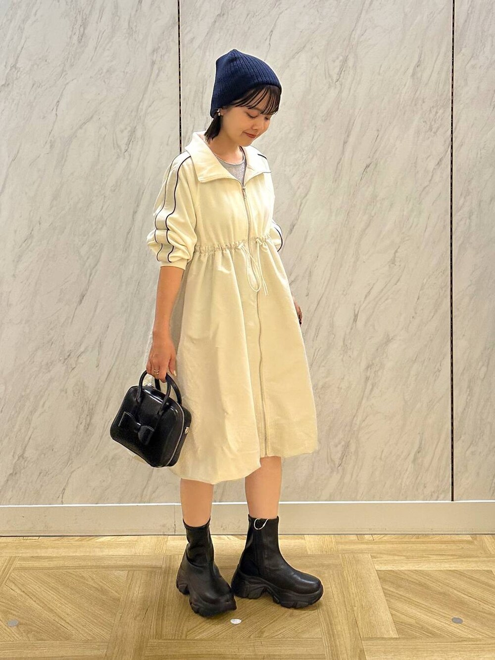 シルバー系のTシャツ/カットソー、ブラック系のボストンバッグ、ブラック系のブーツを着用したレディースの秋コーディネートの2枚目の写真
