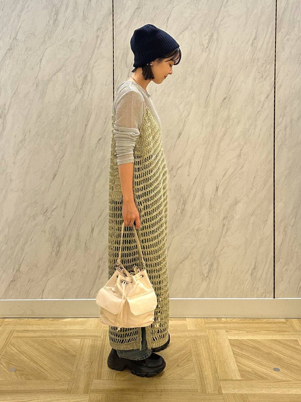 シルバー系のTシャツ/カットソー、ブラック系のスニーカー、ブルー系のデニムパンツを着用したレディースの秋コーディネートの4枚目の写真