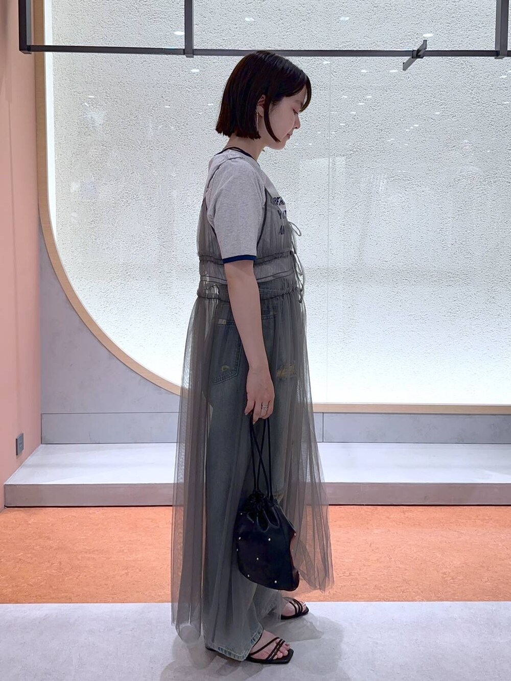 ブラック系のショルダーバッグ、グレー系のTシャツ/カットソー、ブルー系のデニムパンツを着用したレディースの夏コーディネートの3枚目の写真