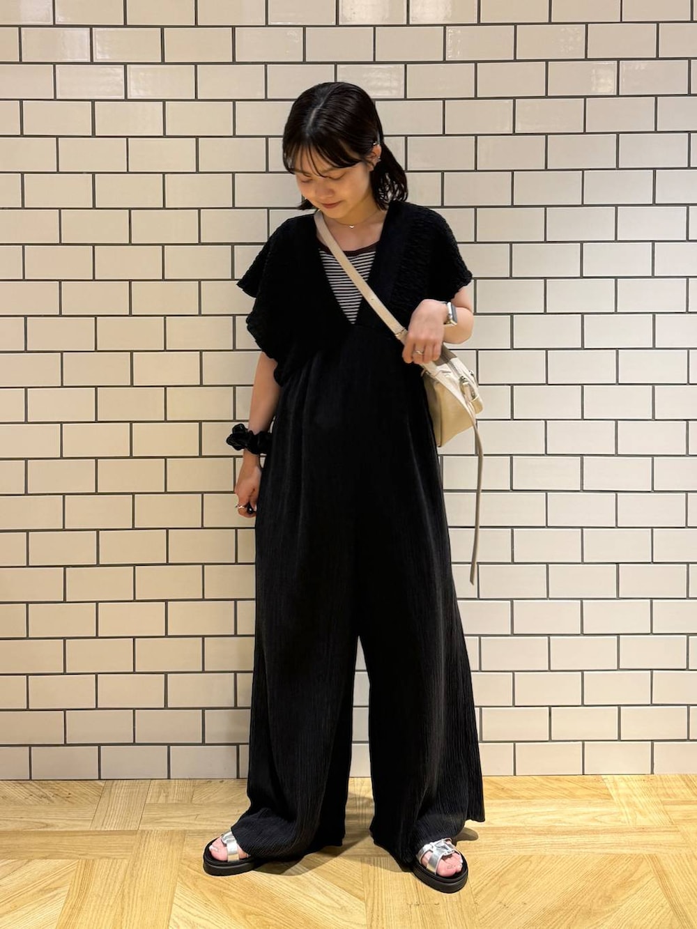 シルバー系のサンダル、ブラック系のサロペット/オーバーオール、ホワイト系のショルダーバッグを着用したレディースの夏コーディネートの3枚目の写真