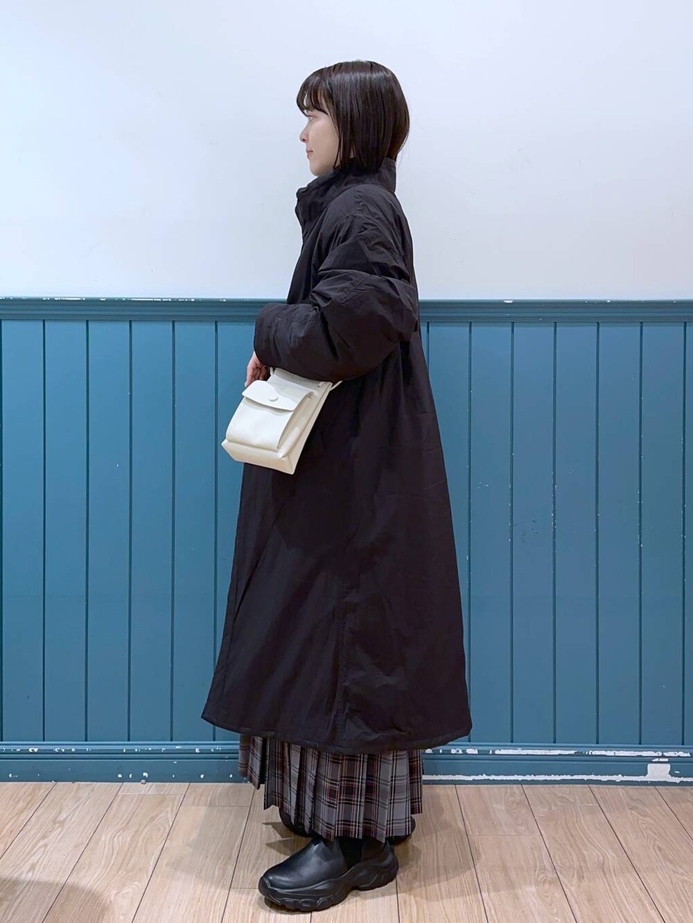 ホワイト系のショルダーバッグ、ブラック系のブーツ、ブラック系のミリタリージャケットを着用したレディースの冬コーディネートの2枚目の写真