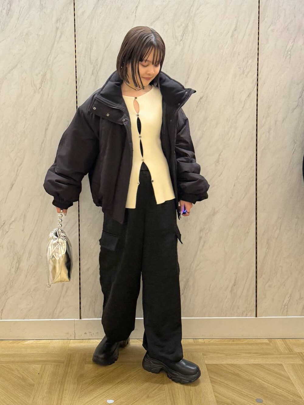 ブラック系のその他アウター、ブラック系のブーツ、シルバー系のショルダーバッグを着用したレディースの冬コーディネートの2枚目の写真