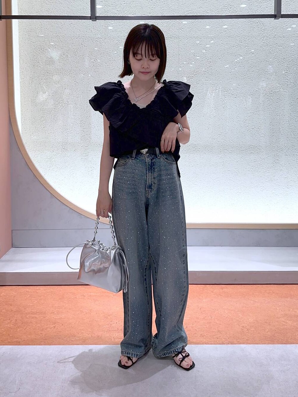 ブラック系のサンダル、シルバー系のショルダーバッグ、ホワイト系のキャミソールを着用したレディースの夏コーディネートの2枚目の写真