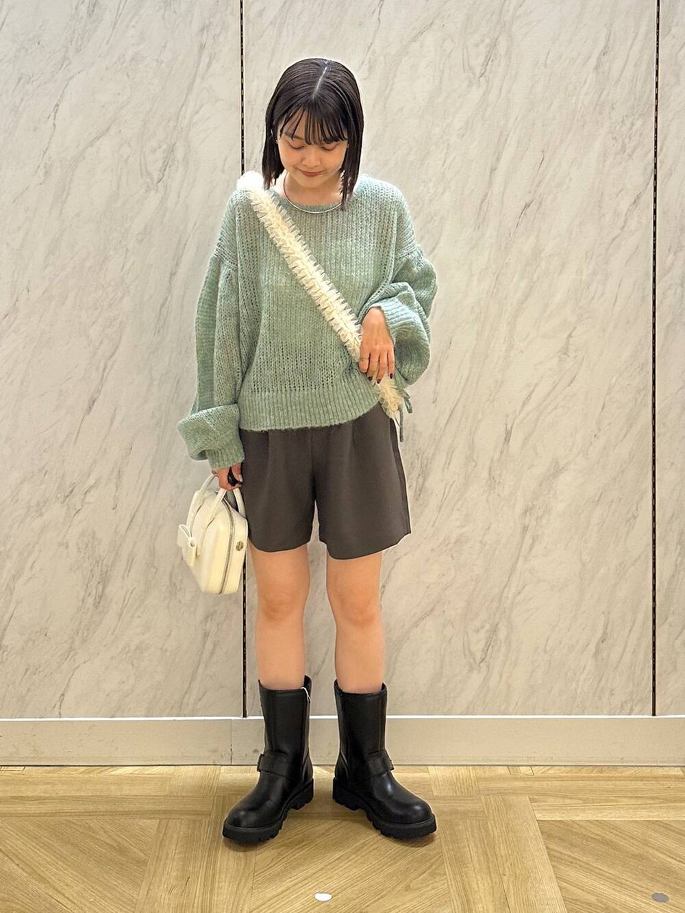 ブラック系のブーツ、ホワイト系のボストンバッグ、グレー系のその他パンツを着用したレディースの秋コーディネートの2枚目の写真