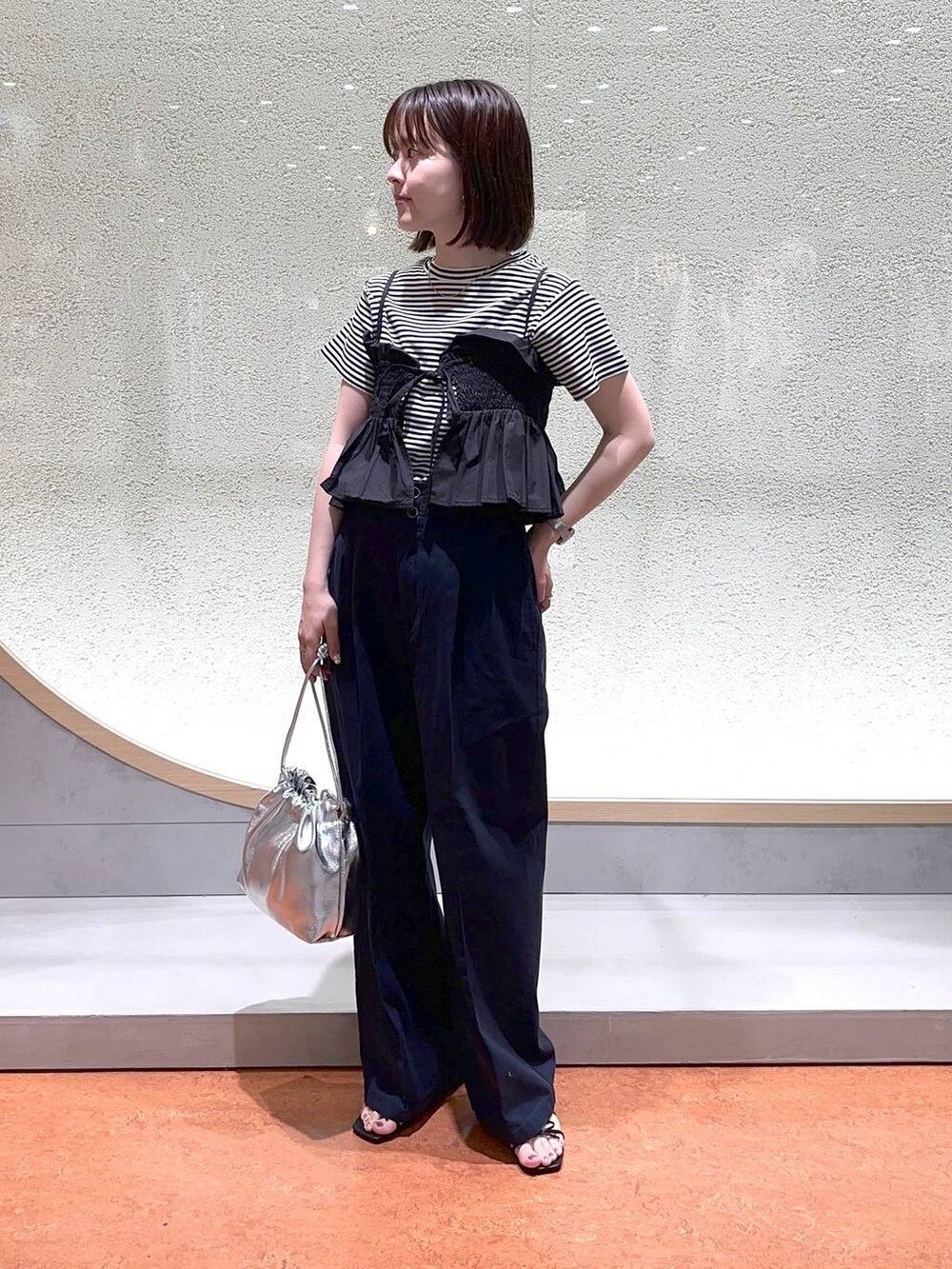 ブルー系のチノパンツ、ブラック系のサンダル、シルバー系のショルダーバッグを着用したレディースの春コーディネートの2枚目の写真