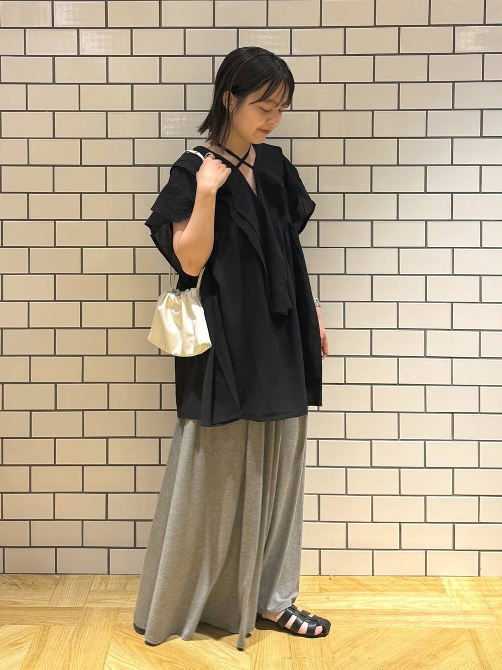 ホワイト系のショルダーバッグ、ブラック系のシャツ/ブラウス、ブラック系のサンダルを着用したレディースの夏コーディネートの2枚目の写真