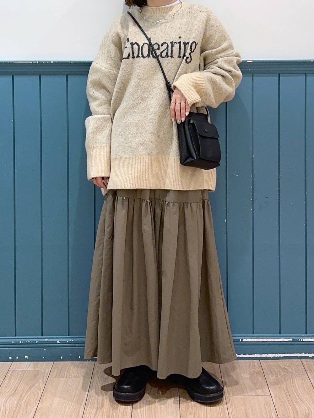 ホワイト系のニット/セーター、ブラック系のショルダーバッグ、グリーン系のスカートを着用したレディースの冬コーディネートの4枚目の写真