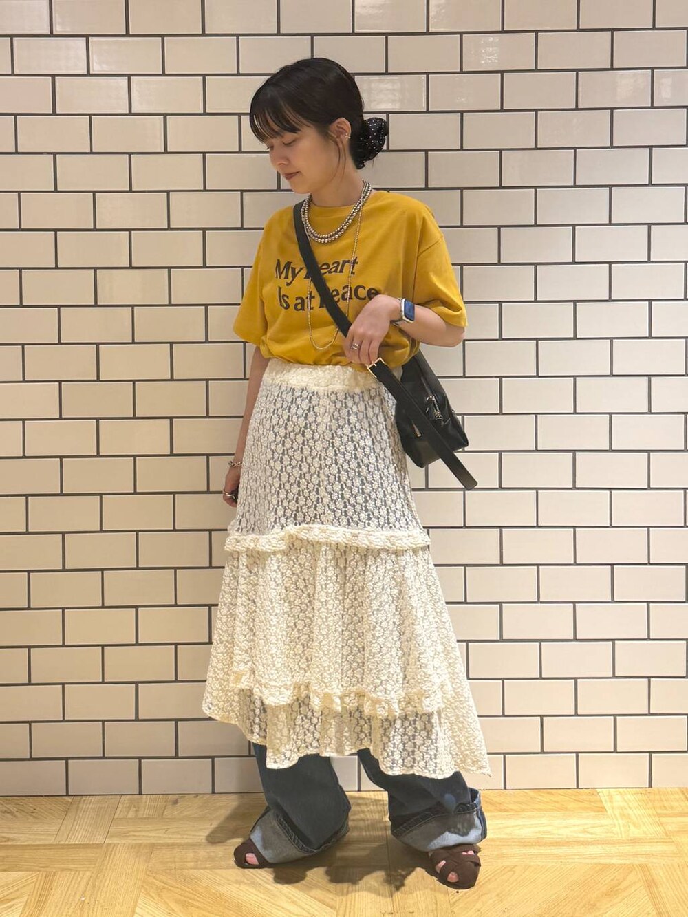 ブラウン系のサンダル、ブルー系のデニムパンツ、ホワイト系のスカートを着用したレディースの夏コーディネートの2枚目の写真