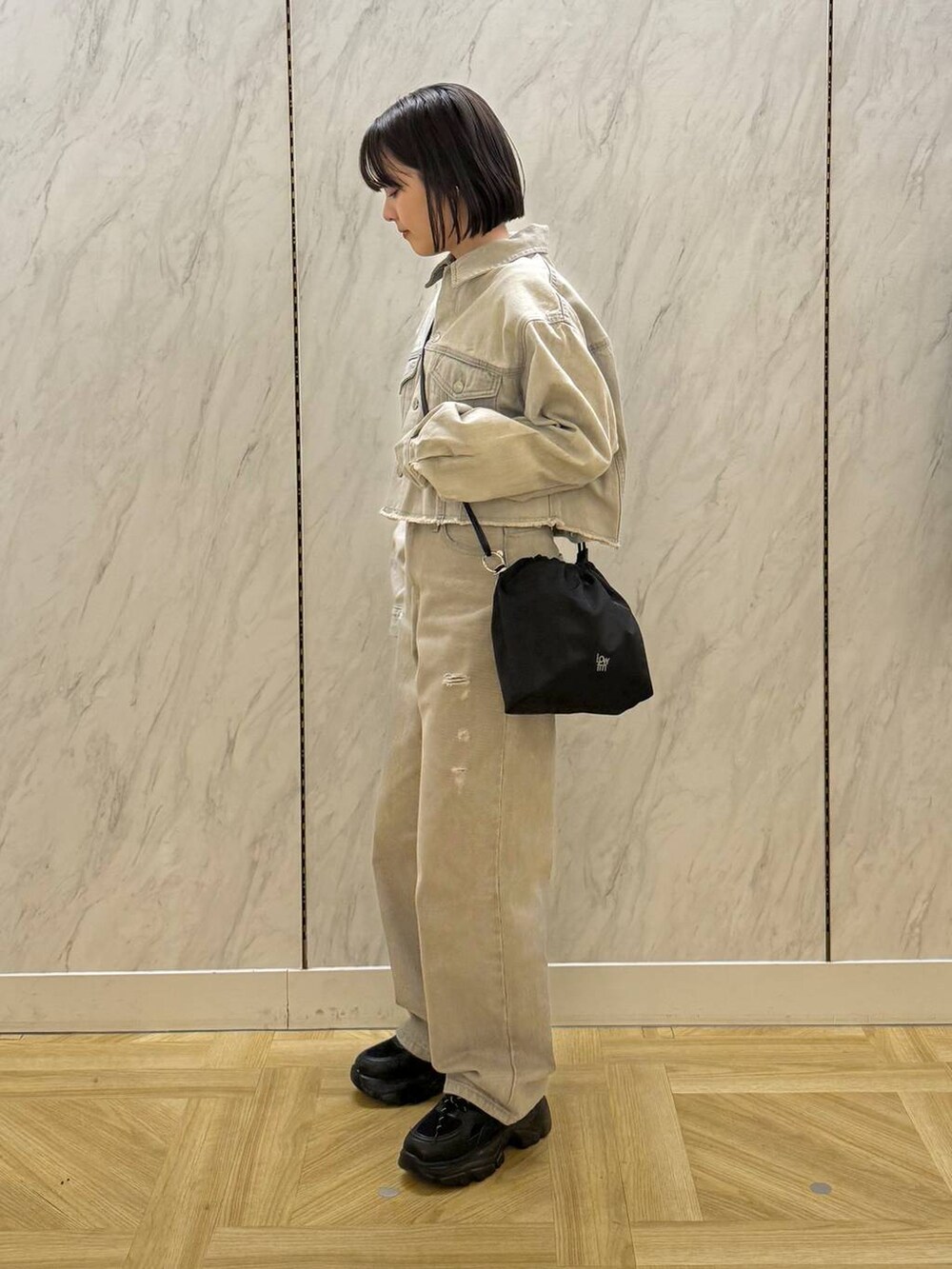 グレー系のデニムジャケット、ブラック系のスニーカー、ブラック系のショルダーバッグを着用したレディースの冬コーディネートの3枚目の写真