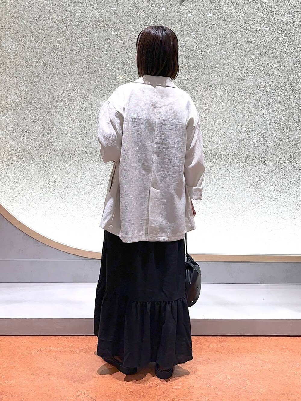 ブラック系のモカシン/デッキシューズ、ブラック系のショルダーバッグ、ホワイト系のテーラードジャケットを着用したレディースの春コーディネートの4枚目の写真