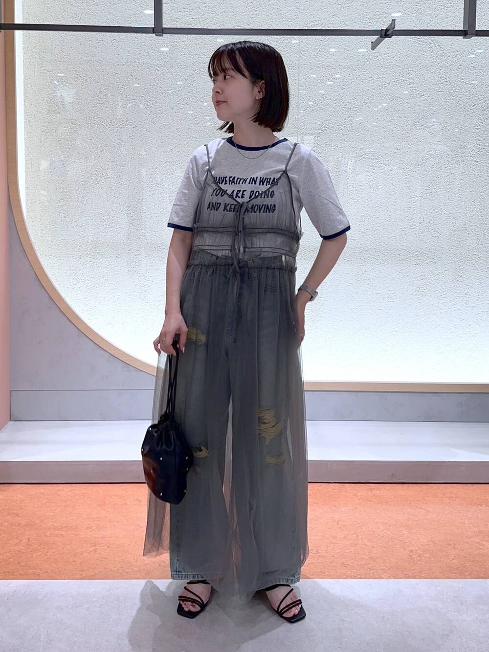 ブラック系のショルダーバッグ、グレー系のTシャツ/カットソー、ブルー系のデニムパンツを着用したレディースの夏コーディネートの2枚目の写真