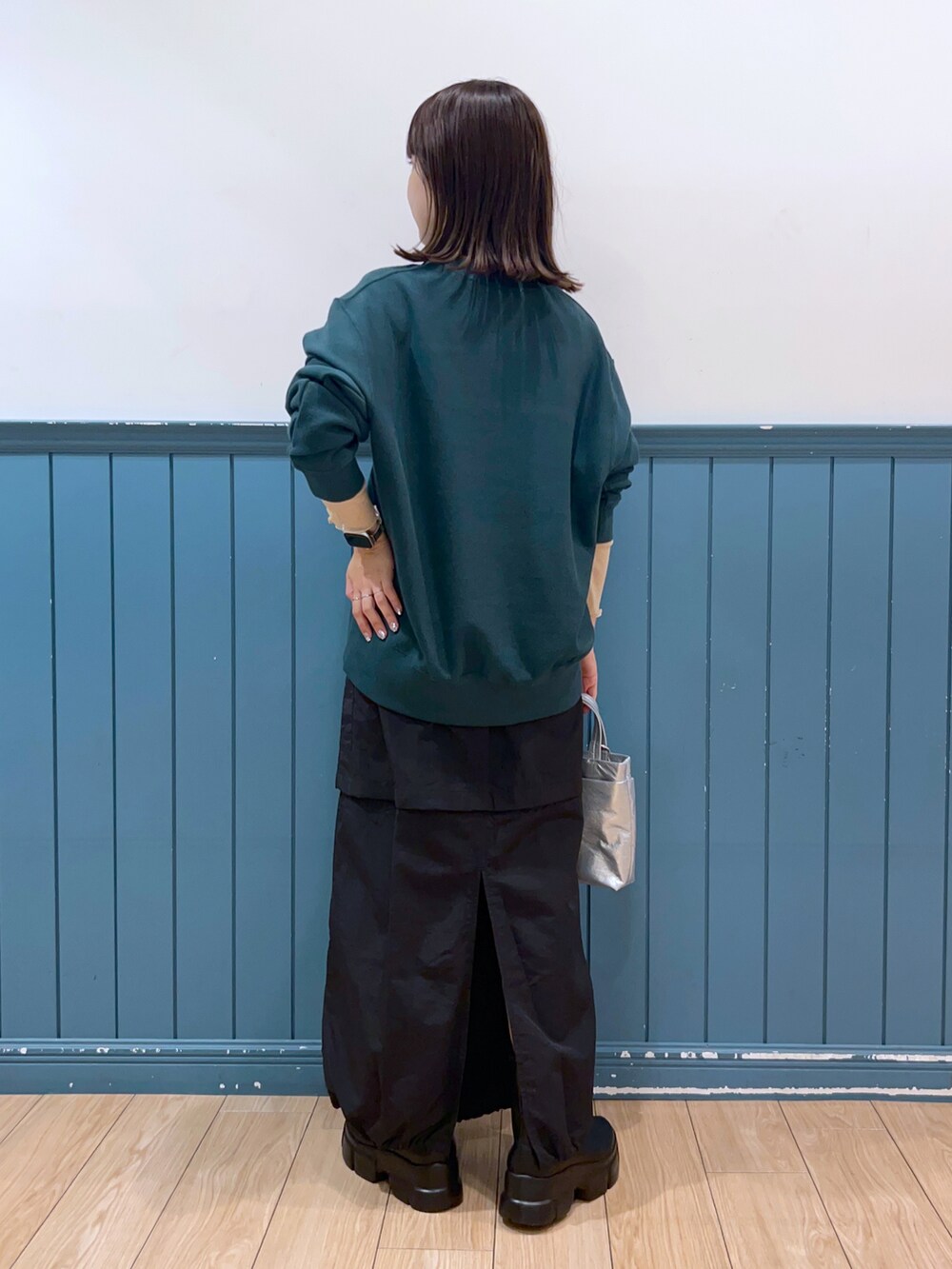 グリーン系のスウェット、ベージュ系のTシャツ/カットソー、ブラック系のスカートを着用したレディースの秋コーディネートの3枚目の写真