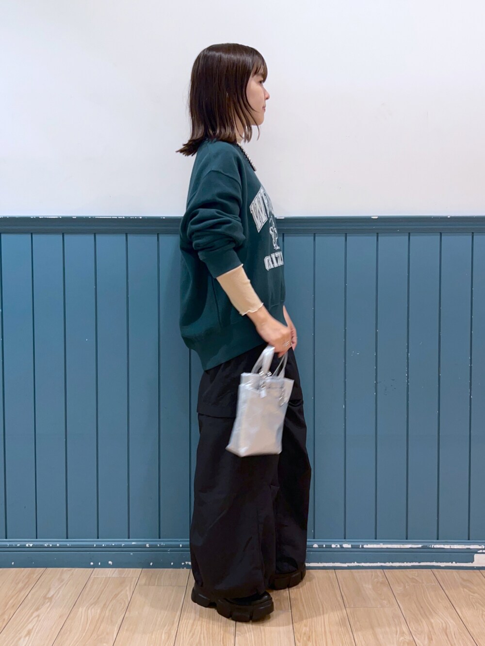 グリーン系のスウェット、ベージュ系のTシャツ/カットソー、ブラック系のスカートを着用したレディースの秋コーディネートの2枚目の写真