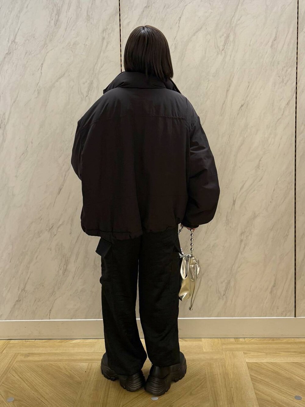 ブラック系のその他アウター、ブラック系のブーツ、シルバー系のショルダーバッグを着用したレディースの冬コーディネートの4枚目の写真