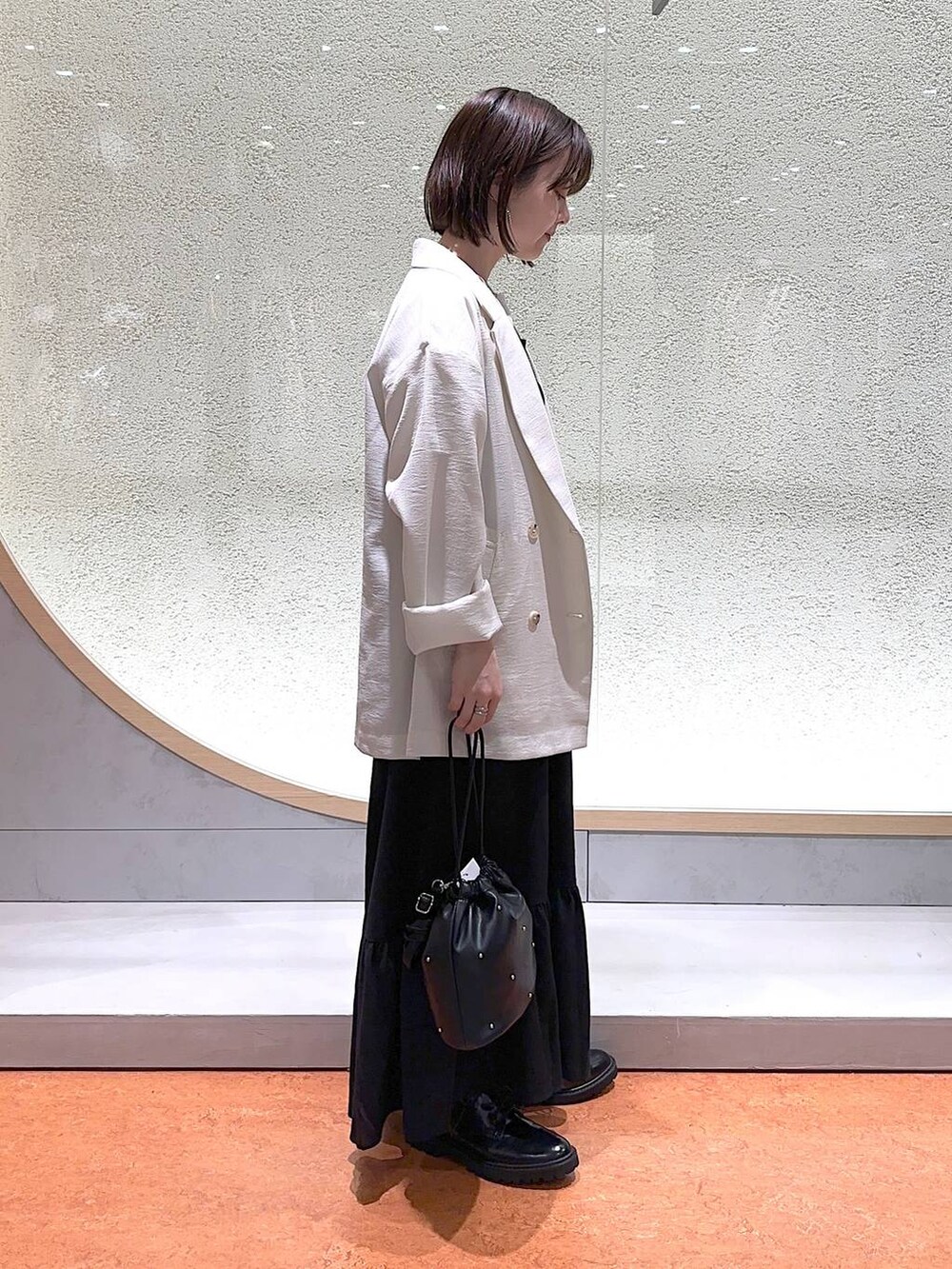ブラック系のモカシン/デッキシューズ、ブラック系のショルダーバッグ、ホワイト系のテーラードジャケットを着用したレディースの春コーディネートの3枚目の写真