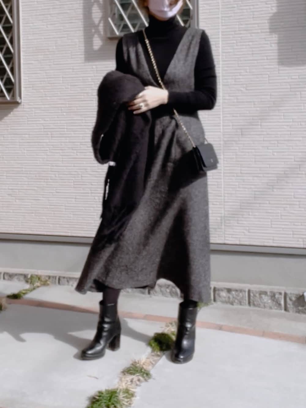 ブラック系のニット/セーター、ブラック系のブーツ、ブラック系のジャンパースカートを着用したレディースの冬コーディネートの2枚目の写真
