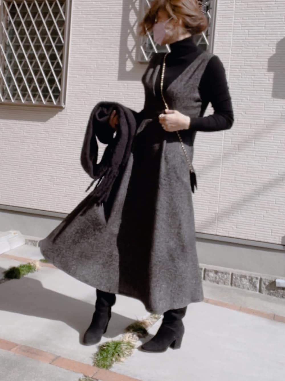 ブラック系のニット/セーター、ブラック系のブーツ、ブラック系のジャンパースカートを着用したレディースの冬コーディネートの3枚目の写真