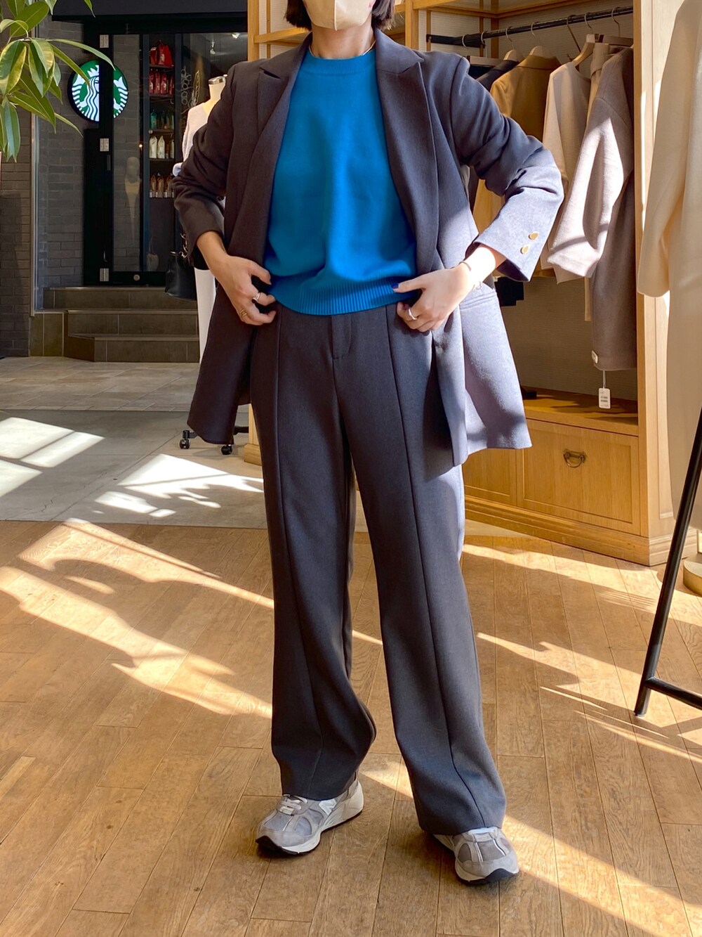 グレー系のテーラードジャケット、グレー系のスラックス、ブルー系のニット/セーターを着用したレディースの冬コーディネートの2枚目の写真