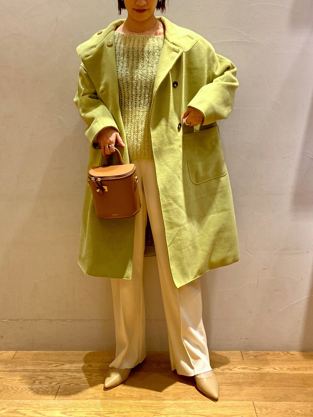 グリーン系のその他アウター、ホワイト系のスラックス、イエロー系のニット/セーターを着用したレディースの冬コーディネートの2枚目の写真