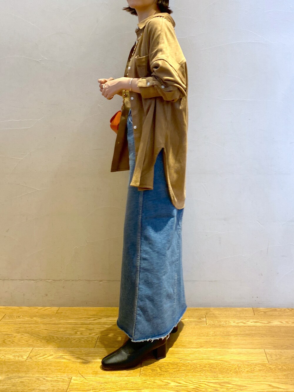 ブルー系のデニムスカート、ベージュ系のシャツ/ブラウス、オレンジ系のトートバッグを着用したレディースの秋コーディネートの2枚目の写真
