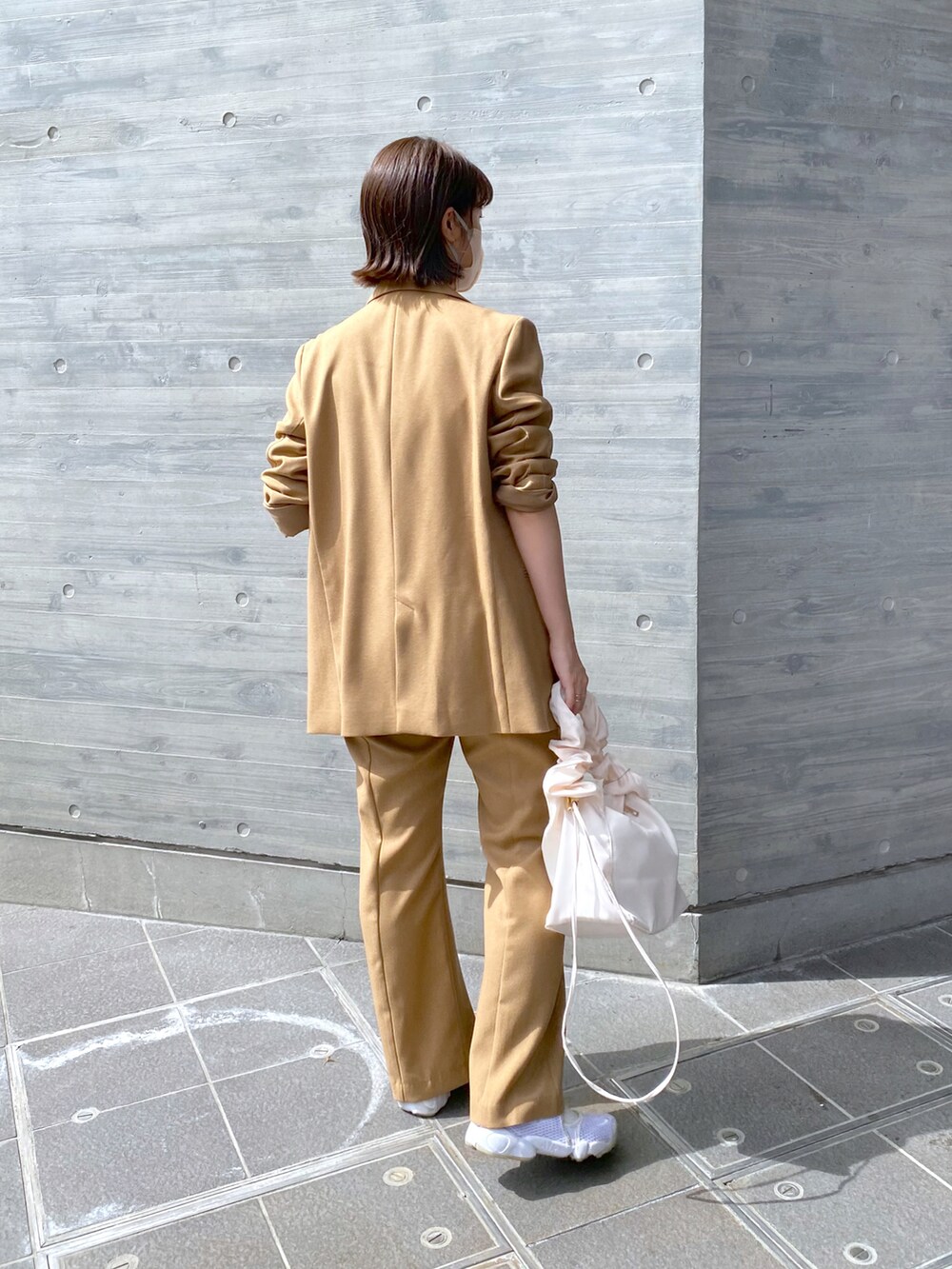 ベージュ系のテーラードジャケット、ベージュ系のスラックス、ホワイト系のショルダーバッグを着用したレディースの秋コーディネートの2枚目の写真