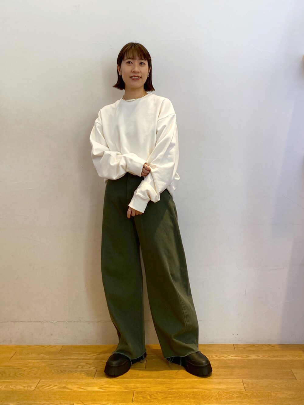 ベージュ系のベスト、ホワイト系のスウェット、グリーン系のショルダーバッグを着用したレディースの秋コーディネートの2枚目の写真