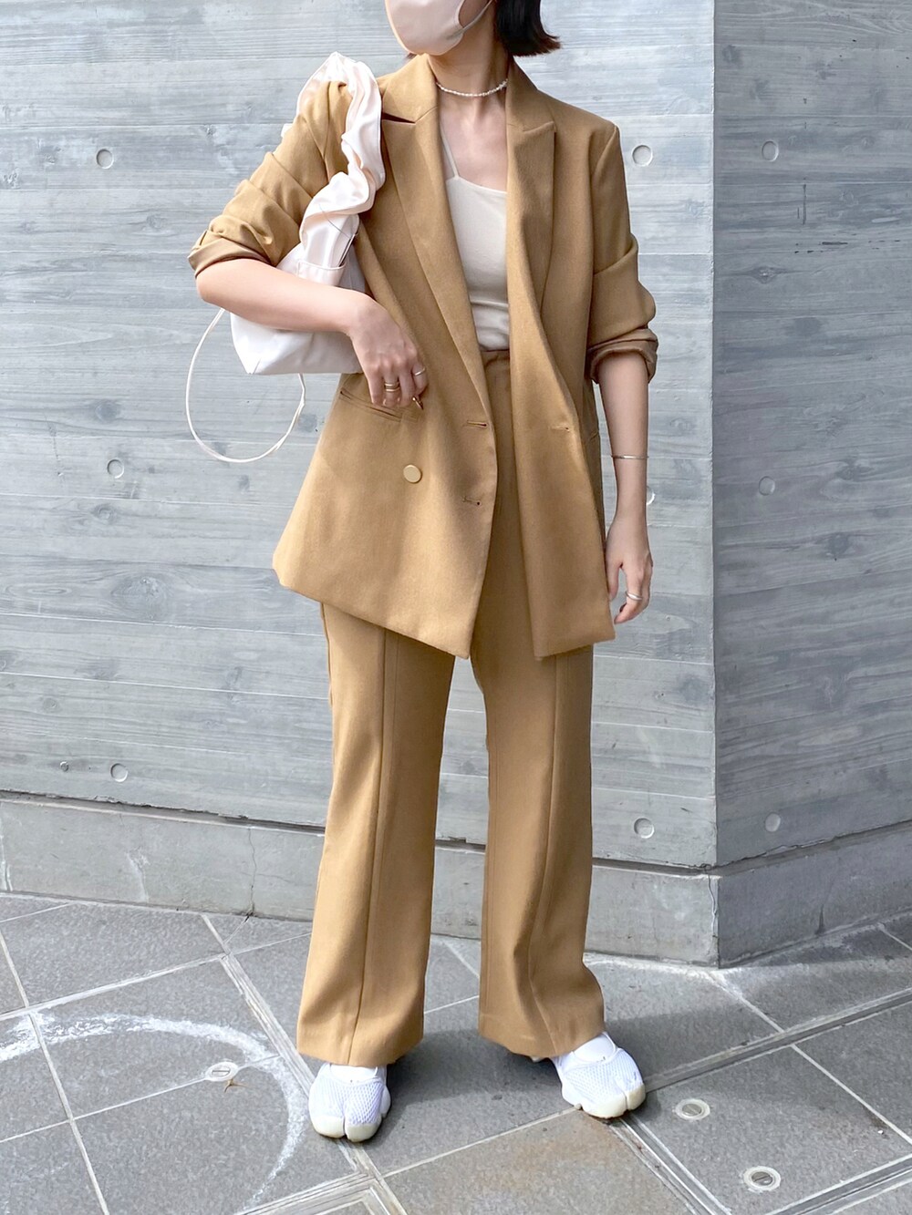 ベージュ系のテーラードジャケット、ベージュ系のスラックス、ホワイト系のショルダーバッグを着用したレディースの秋コーディネートの3枚目の写真