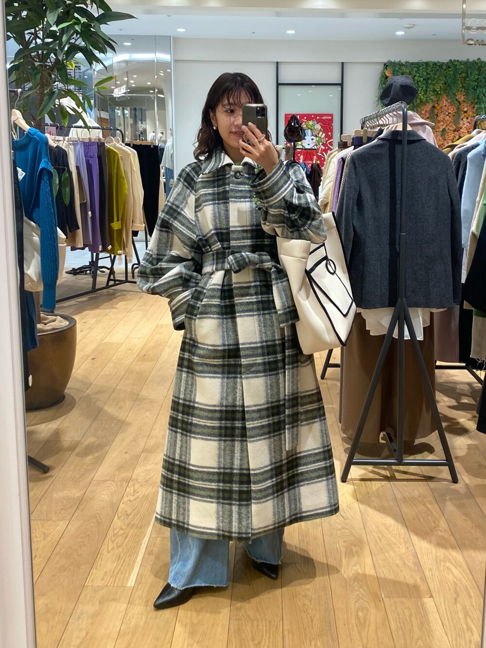 グリーン系のステンカラーコート、グリーン系のニット/セーター、ホワイト系のキャミソールを着用したレディースの冬コーディネートの2枚目の写真