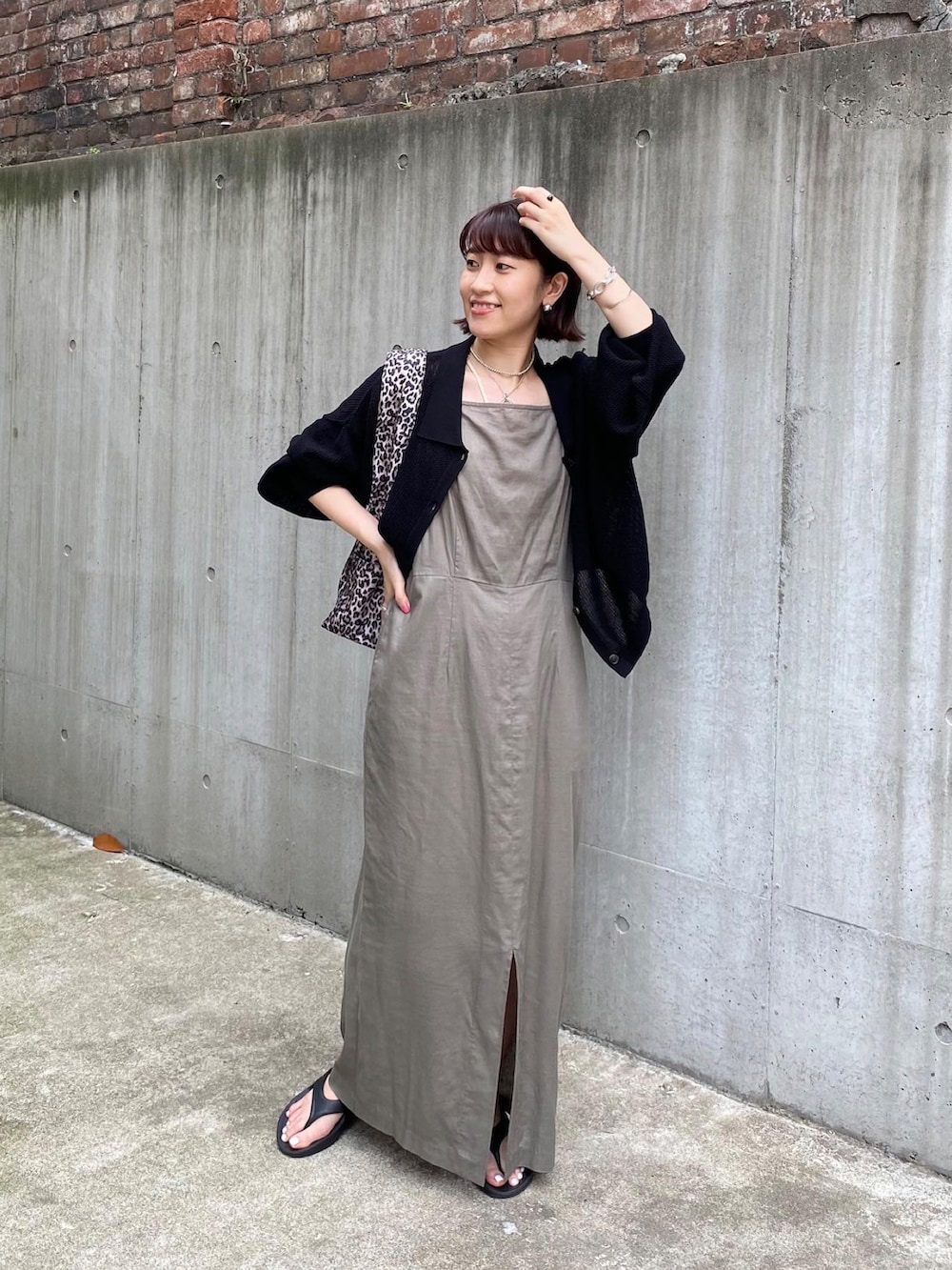 グリーン系のワンピース、ブラック系のカーディガン/ボレロ、ブラック系のサンダルを着用したレディースの夏コーディネートの2枚目の写真