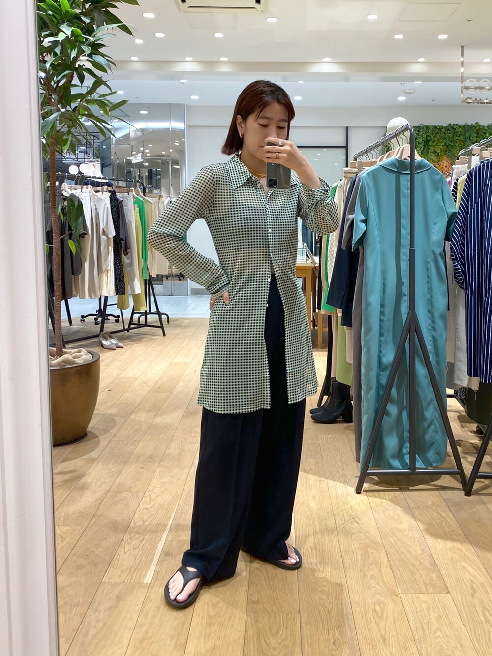 グリーン系のトップス、グレー系のキャミソール、ブルー系のスラックスを着用したレディースの春コーディネートの2枚目の写真