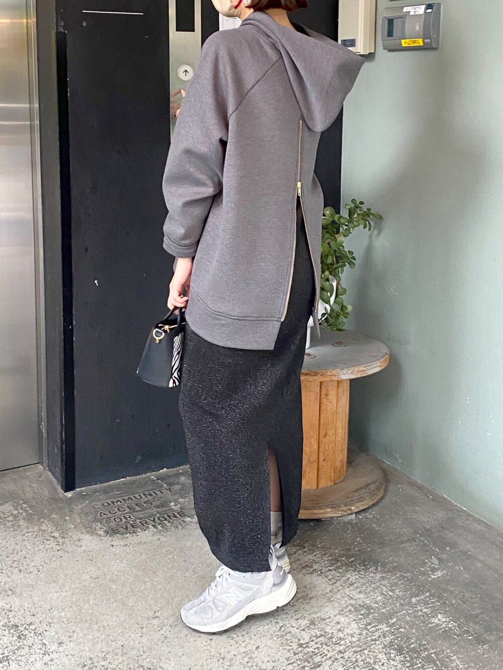 グレー系のパーカー、ブラック系のスカート、ブラック系のショルダーバッグを着用したレディースの秋コーディネートの3枚目の写真