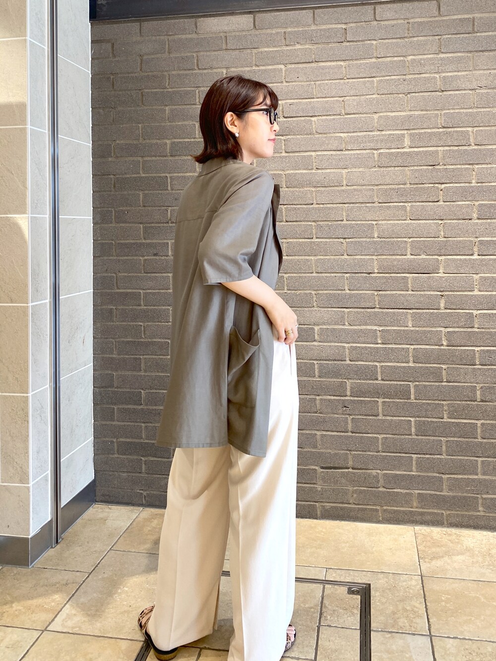 ホワイト系のスラックス、ブラック系のキャミソール、ホワイト系のトートバッグを着用したレディースの夏コーディネートの3枚目の写真