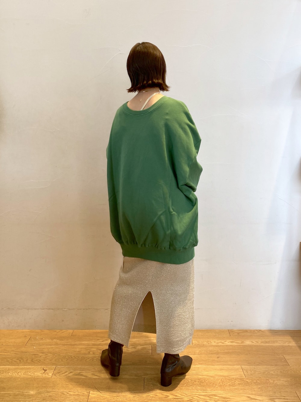 グリーン系のスウェット、ゴールド系のスカートを着用したレディースの秋コーディネートの2枚目の写真