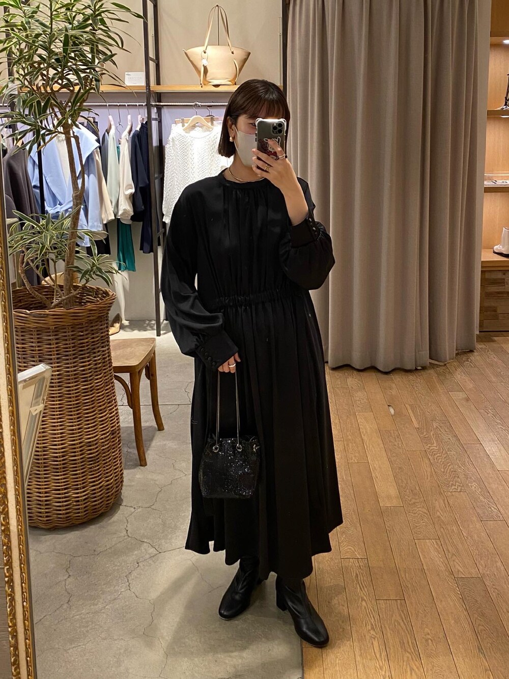 ブラック系のワンピース、ブラック系のショルダーバッグ、ブラック系のブーツを着用したレディースの冬コーディネートの2枚目の写真