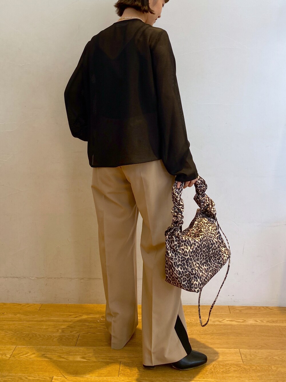 ブラック系のシャツ/ブラウス、ベージュ系のスラックス、ブラック系のブーツを着用したレディースの夏コーディネートの2枚目の写真