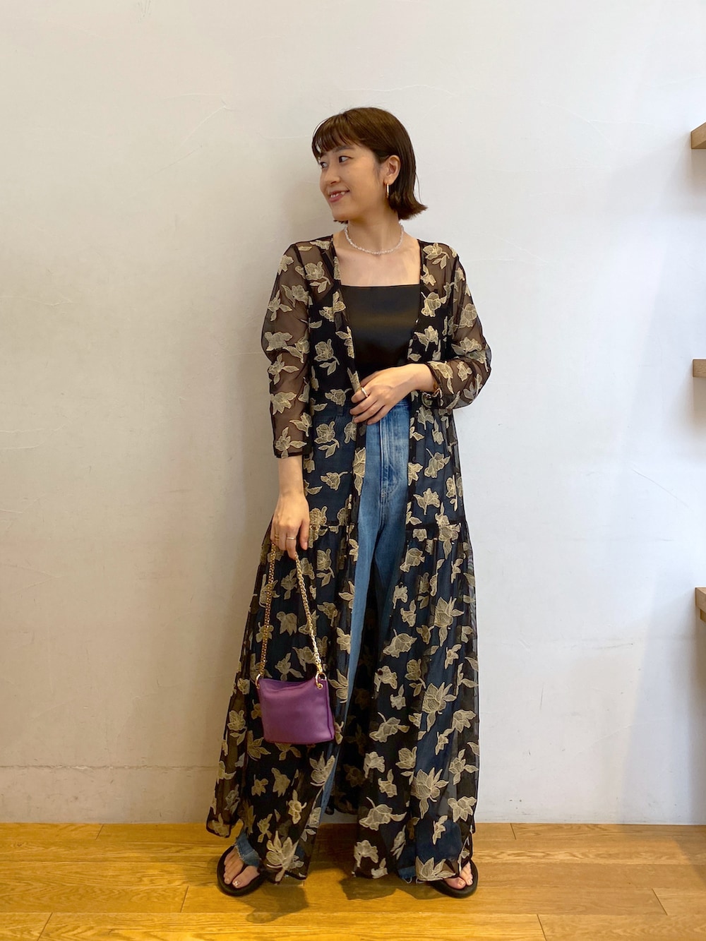 ブラック系のワンピース、パープル系のショルダーバッグ、ブルー系のデニムパンツを着用したレディースの秋コーディネートの2枚目の写真