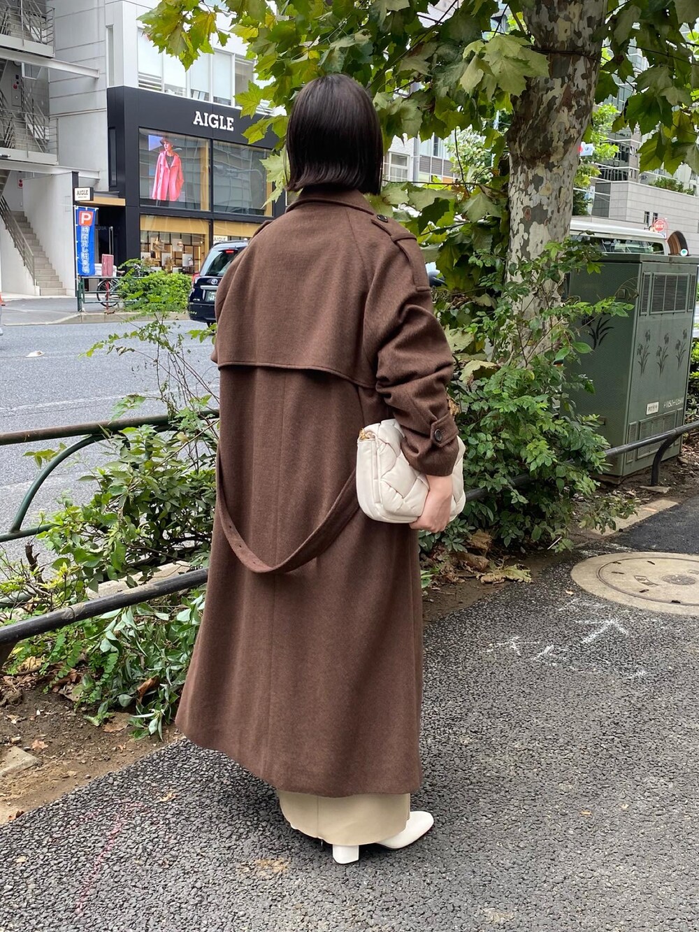 ブラウン系のトレンチコート、ベージュ系のニット/セーター、ベージュ系のスカートを着用したレディースの秋コーディネートの2枚目の写真