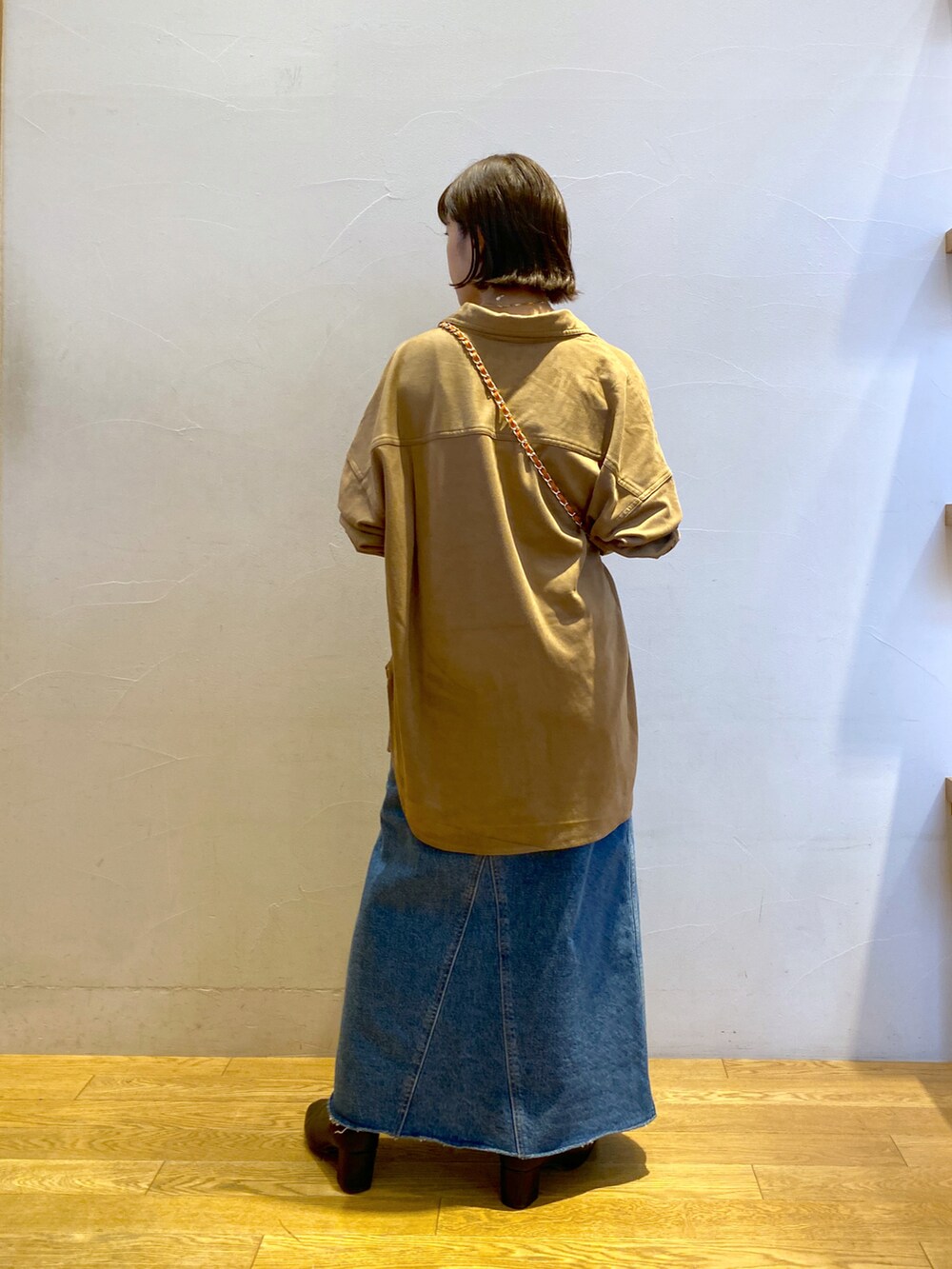 ブルー系のデニムスカート、ベージュ系のシャツ/ブラウス、オレンジ系のトートバッグを着用したレディースの秋コーディネートの3枚目の写真