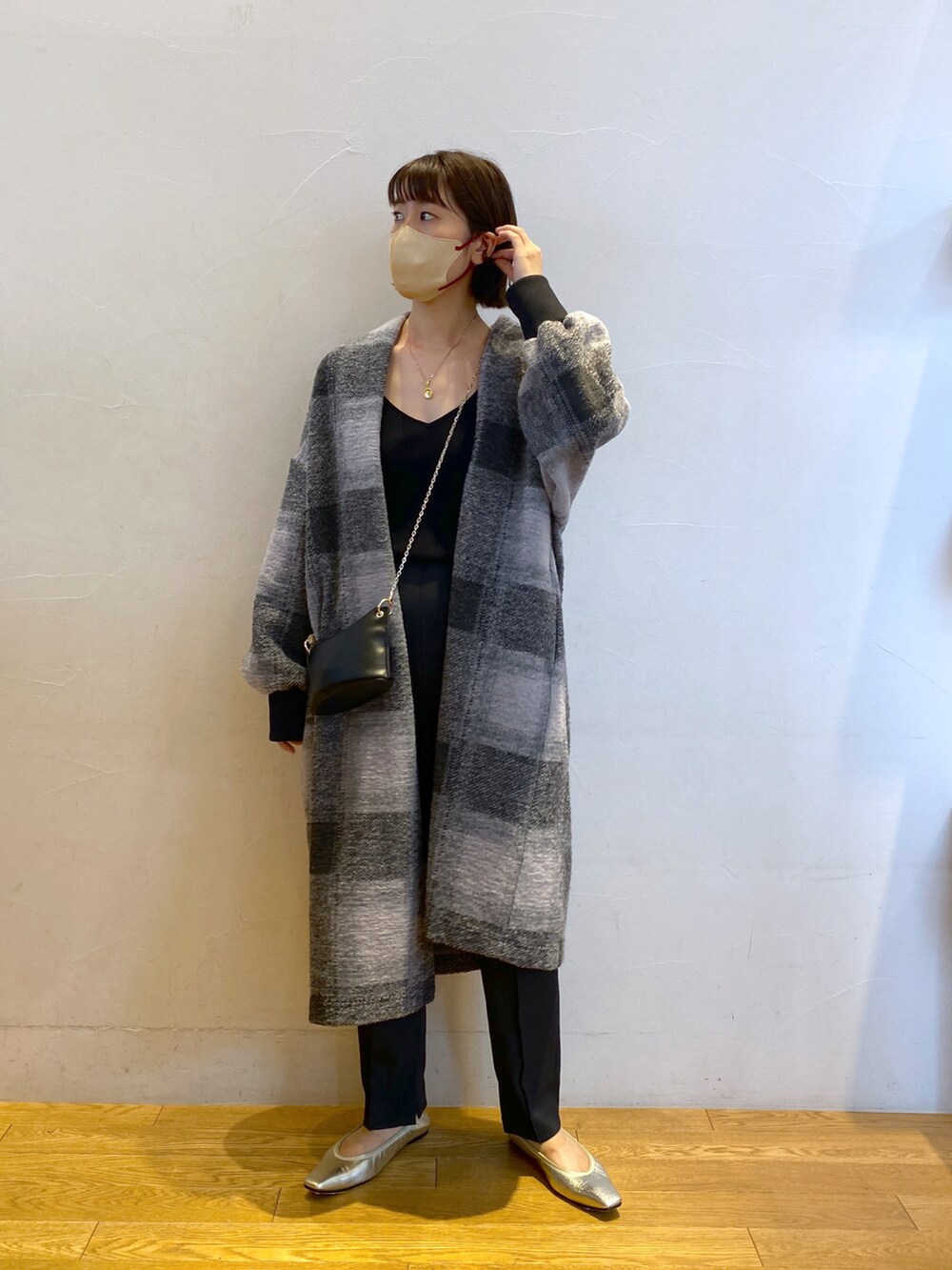 グレー系のノーカラーコート、ブラック系のタンクトップ、ブラック系のショルダーバッグを着用したレディースの夏コーディネートの2枚目の写真