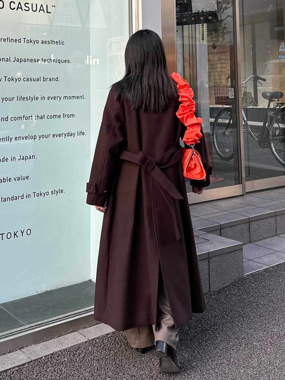 ブラウン系のチェスターコート、オレンジ系のショルダーバッグを着用したレディースの冬コーディネートの4枚目の写真